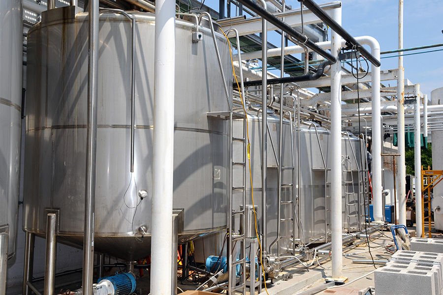 Beverage processing facility featuring stainless steel tanks, piping systems, and industrial equipment for food production automation.