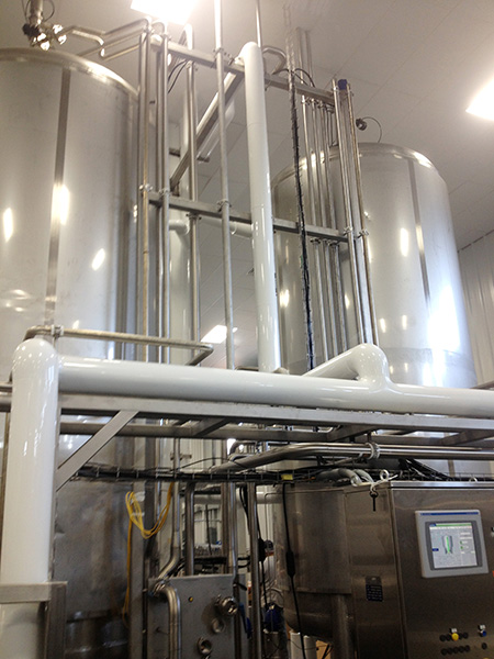 Beverage processing equipment featuring stainless steel tanks, piping systems, and control panel, illustrating CHL Systems' beverage facility upgrade and automation solutions.