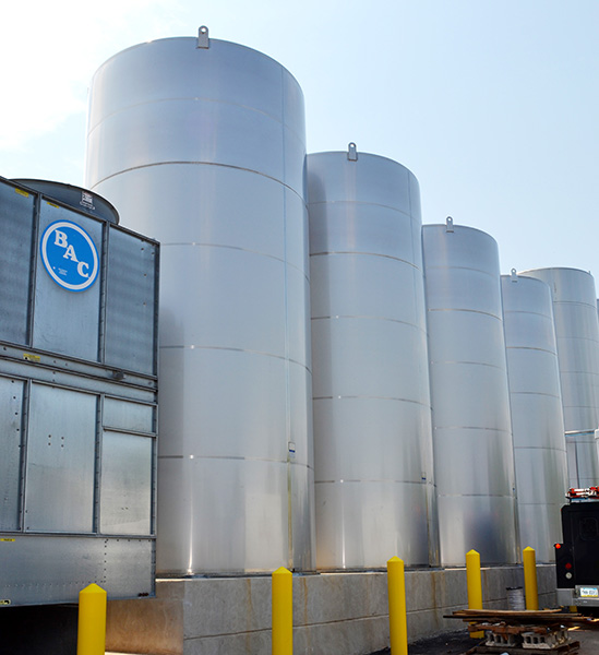 Beverage facility upgrade featuring multiple stainless steel storage tanks and a cooling unit, showcasing CHL Systems' automation solutions for food processing and material handling.