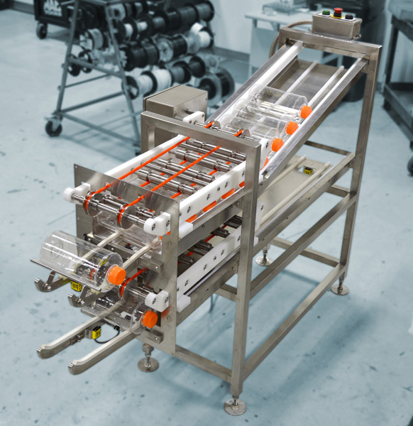 Bottle conveyor system designed for food processing automation, featuring transparent tubes and stainless steel frame, in a production environment.