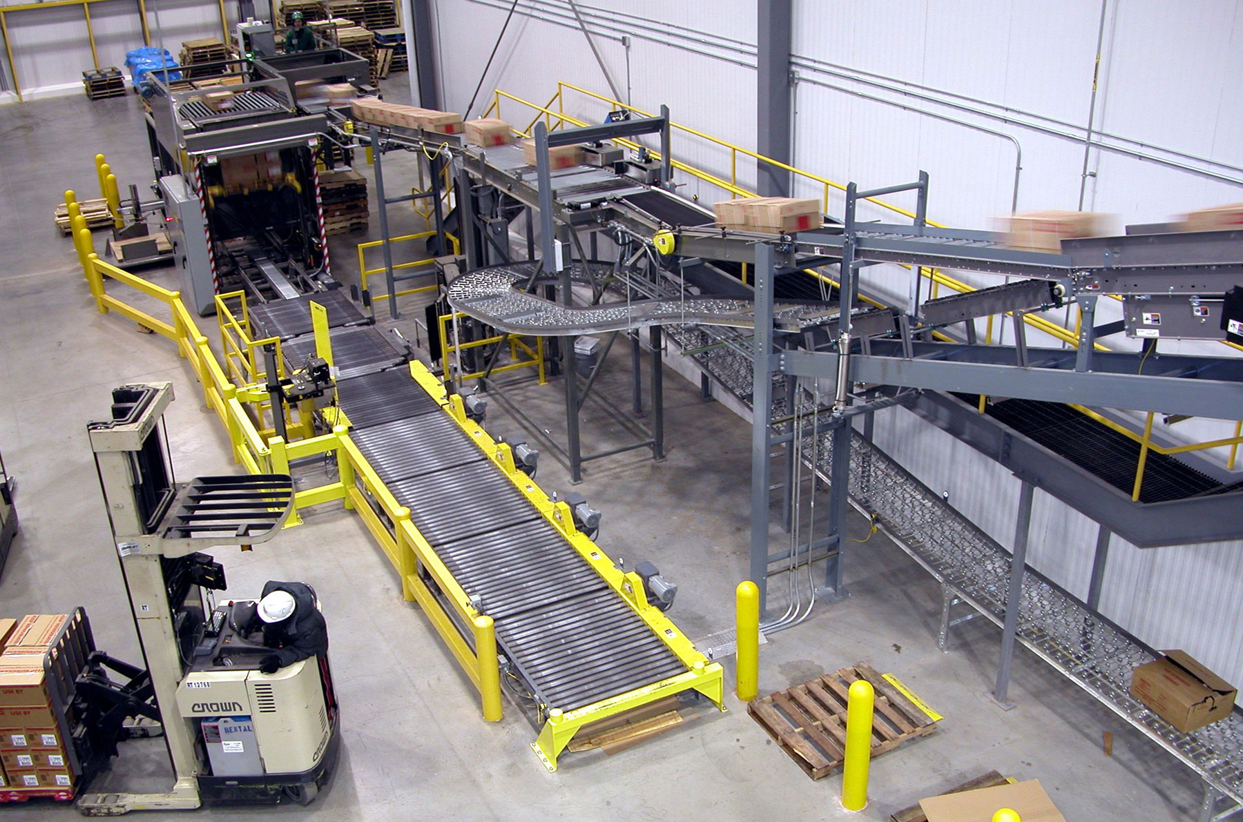 Case-handling conveyor system in a warehouse setting with a forklift, showcasing automated material handling solutions by CHL Systems Inc.