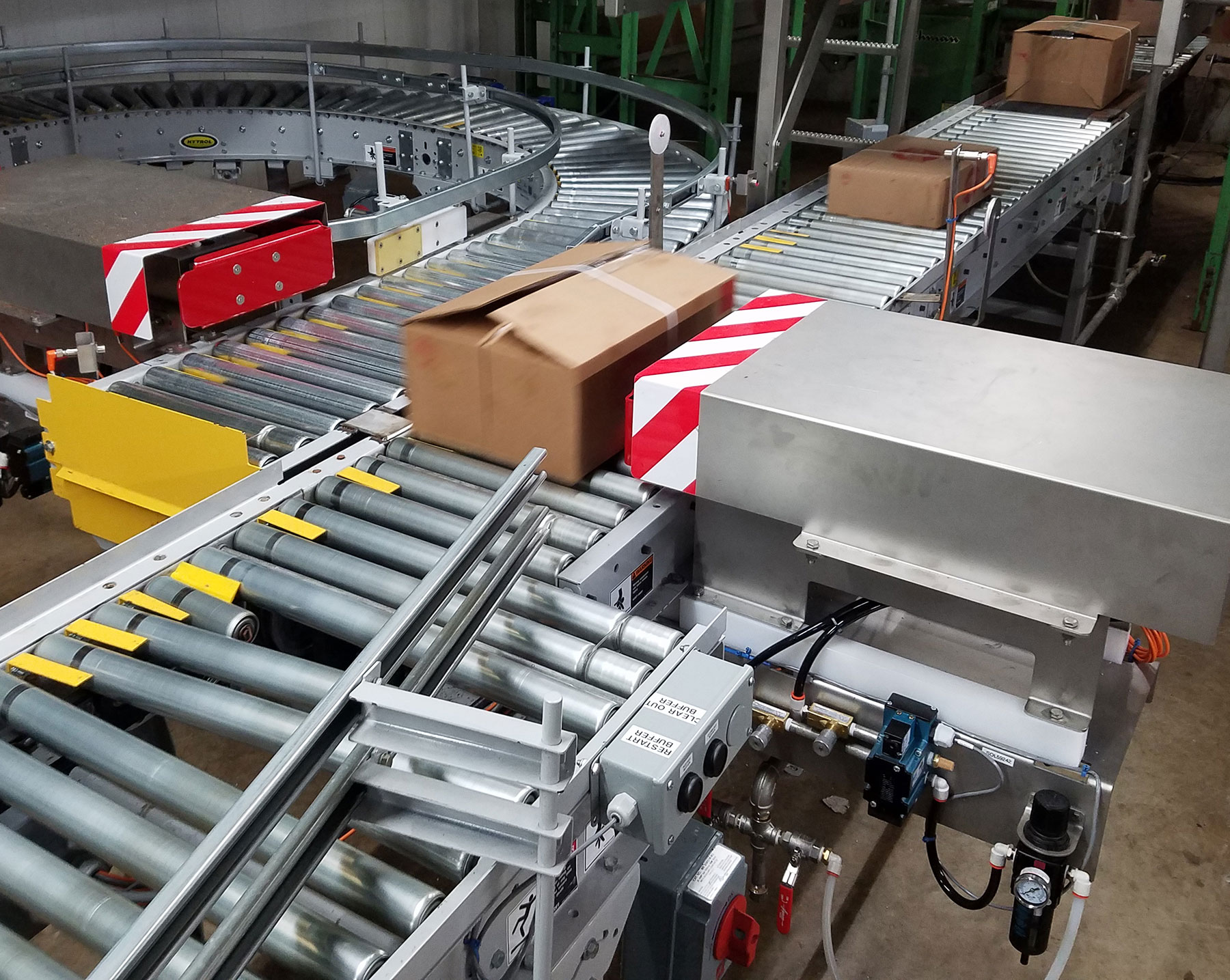 Case-handling conveyor system with boxes moving along roller tracks, featuring safety barriers and automated components, relevant to CHL Systems' food processing and automation solutions.