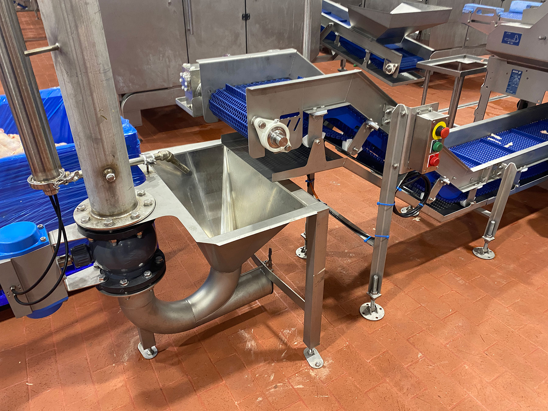 Custom conveyor system with integrated dumper and processing line equipment, featuring stainless steel components and blue conveyor belts for food processing automation.