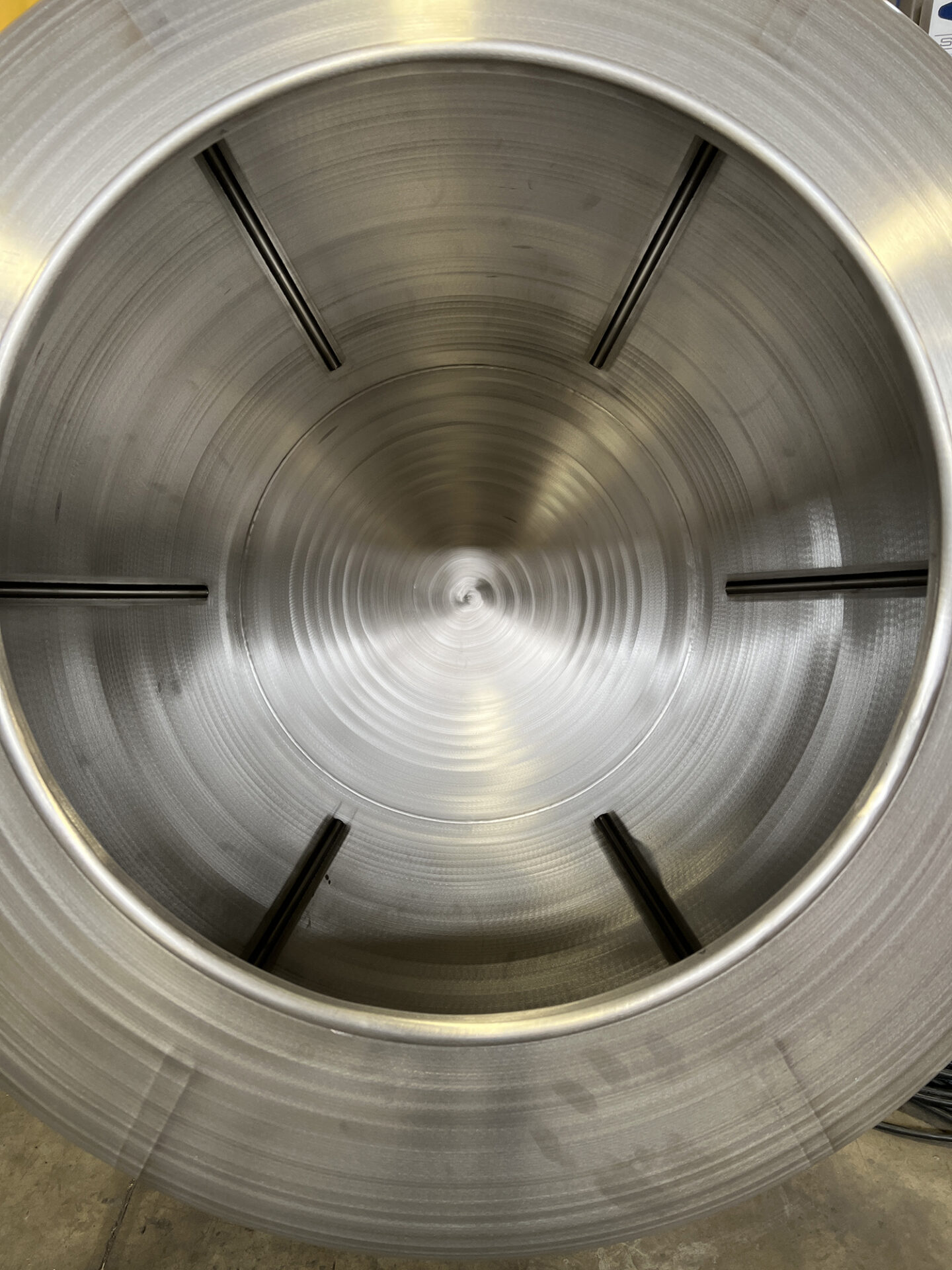 Interior view of a stainless steel batching tank mixer, showcasing smooth surfaces and structural supports, relevant to CHL Systems' food processing automation equipment.