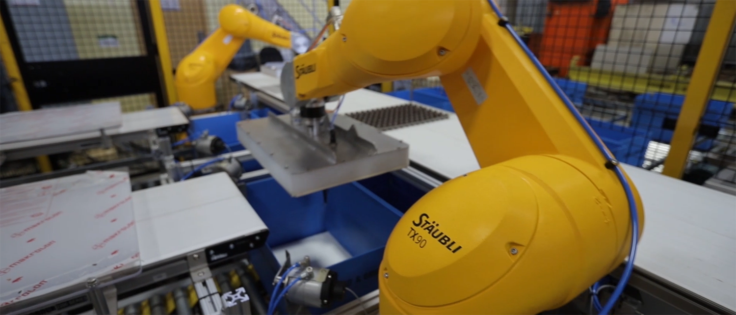 Robotic palletizer with Staubli TX90 arms in a food processing facility, positioned above conveyor systems, demonstrating automation in material handling and packaging solutions.