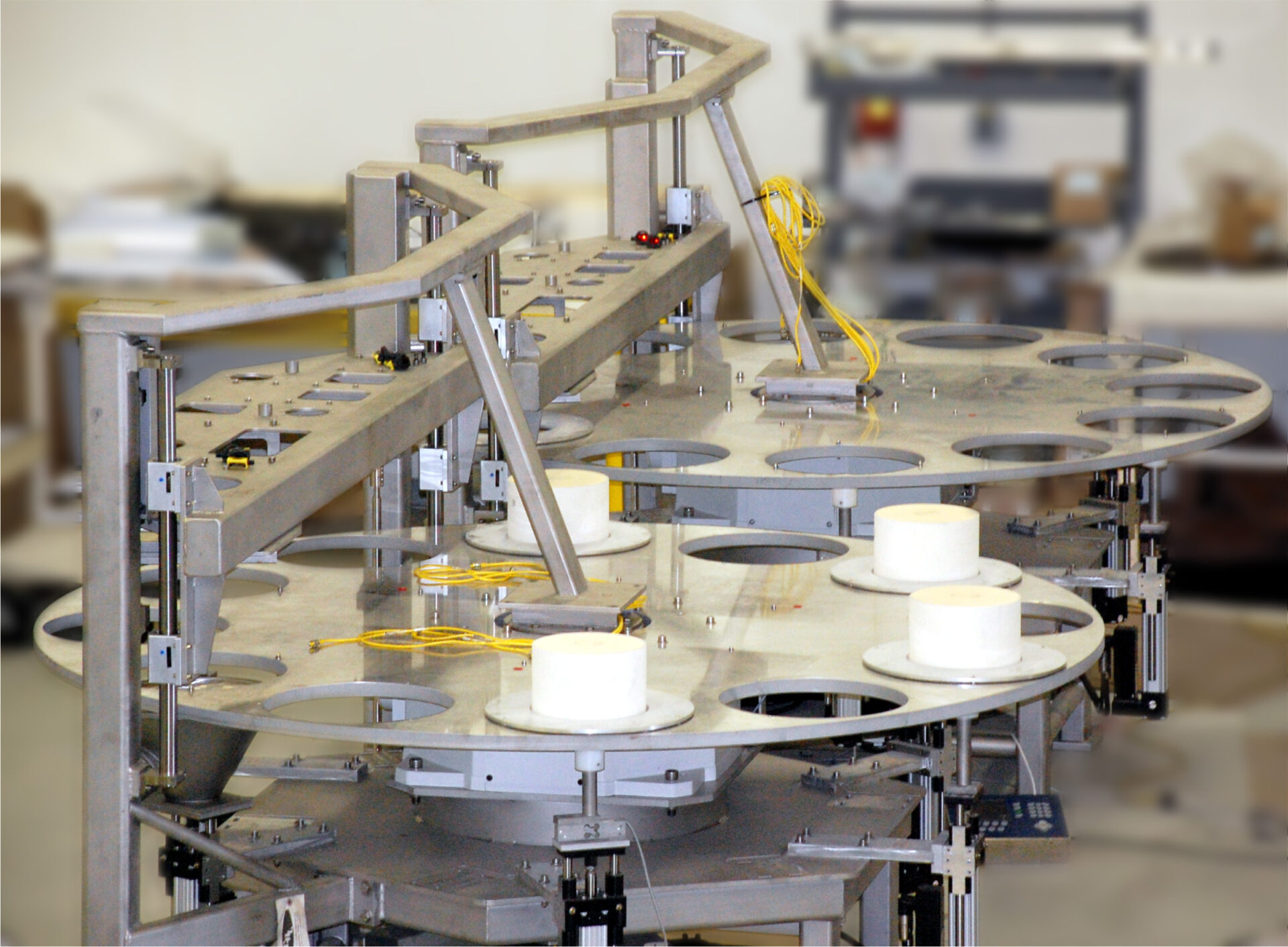 Rotary table with multiple circular platforms and white cylindrical objects, designed for food processing and automation solutions by CHL Systems Inc.