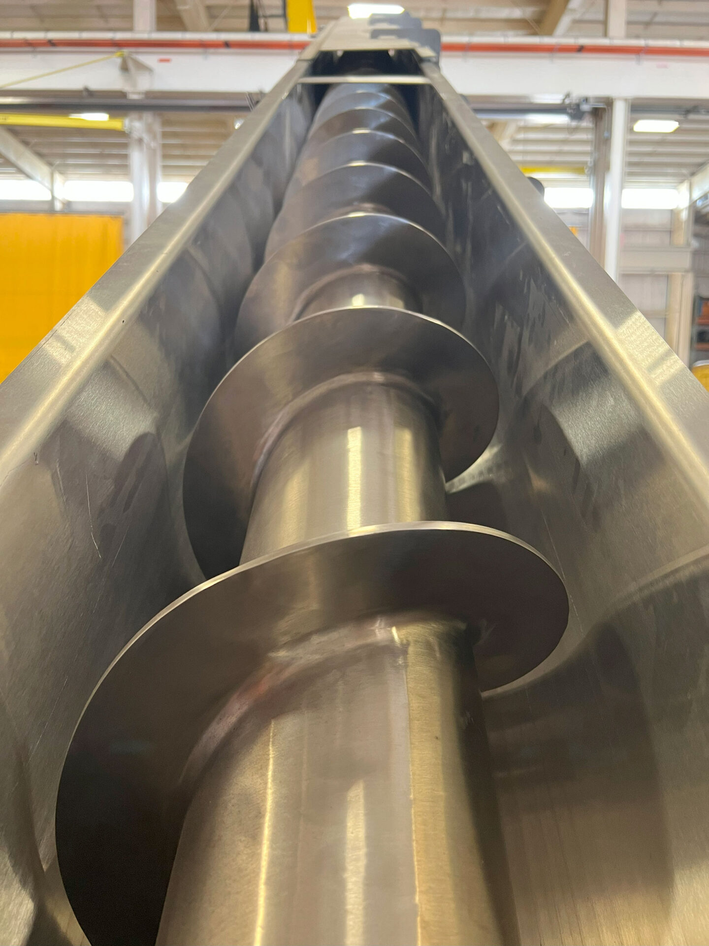 Screw conveyor interior view showcasing spiral auger mechanism, designed for efficient material handling in food processing automation systems by CHL Systems Inc.