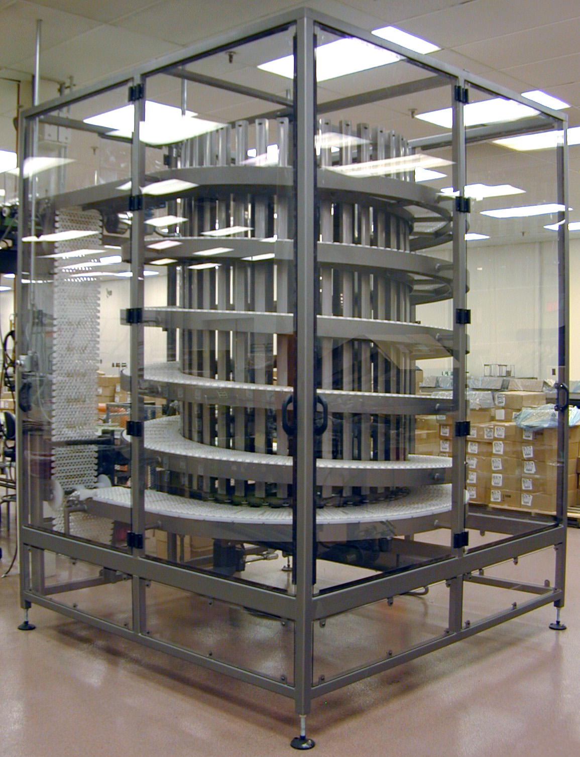 Spiral box conveyor system enclosed in protective casing, designed for efficient material handling in food processing automation.