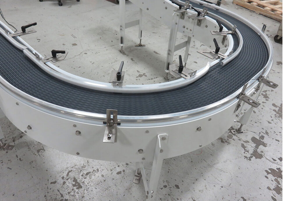 Curved 180 box conveyor system with a black rubber belt and metal framework, designed for efficient material handling in food processing automation.