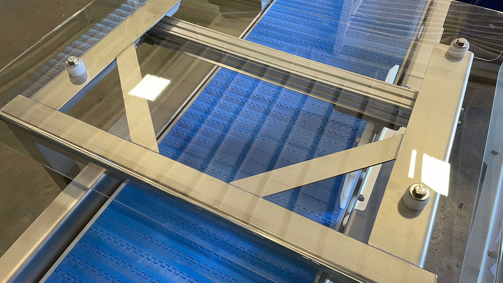 Metal detector conveyor system featuring a blue conveyor belt and stainless steel frame, designed for detecting metal contaminants in food processing applications.