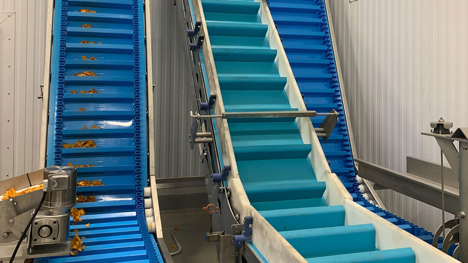 Z-conveyor system with blue linked buckets transporting materials, designed for vertical and angled movement in food processing applications.