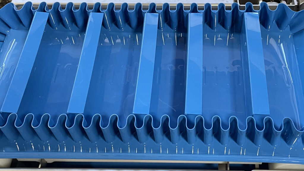 Modular plastic conveyor belt with flights and friction tops for versatile product handling in food processing applications.