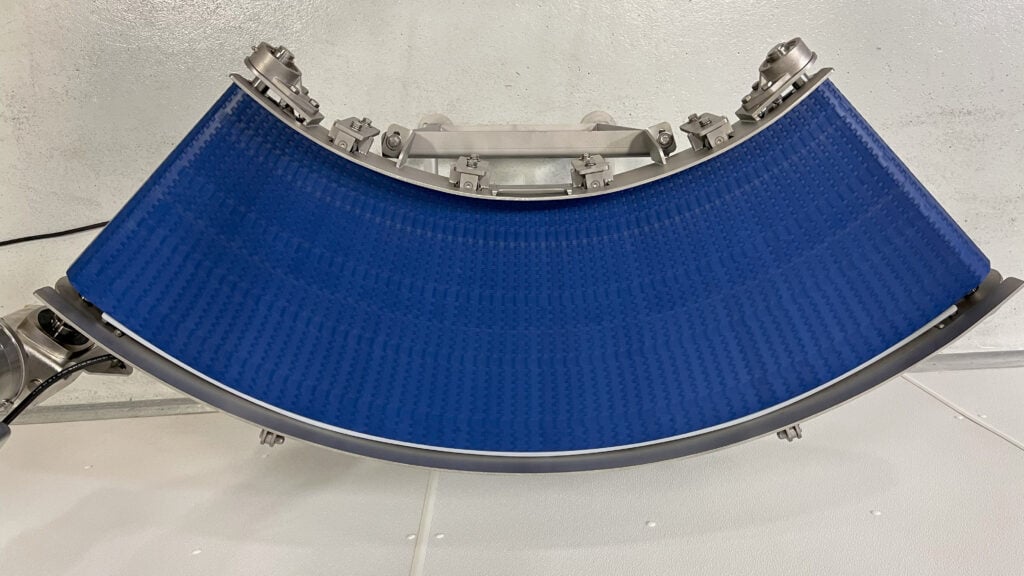 Modular plastic conveyor belt in a curved design, showcasing versatility for protein processing applications.