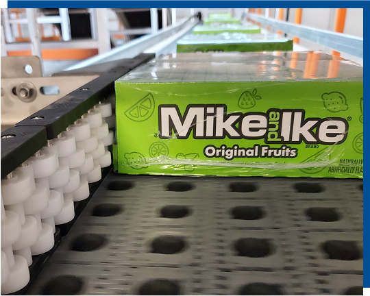 Mike and Ike Original Fruits packaging on conveyor system, showcasing efficient product flow in upgraded candy packaging line.