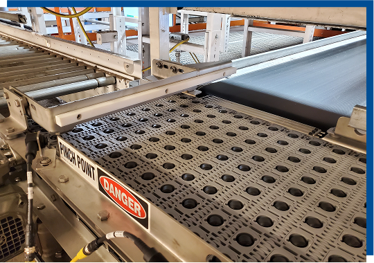 Conveyor system with pinch point warning and safety signage, illustrating CHL Systems' focus on efficient and safe material handling solutions in industrial settings.