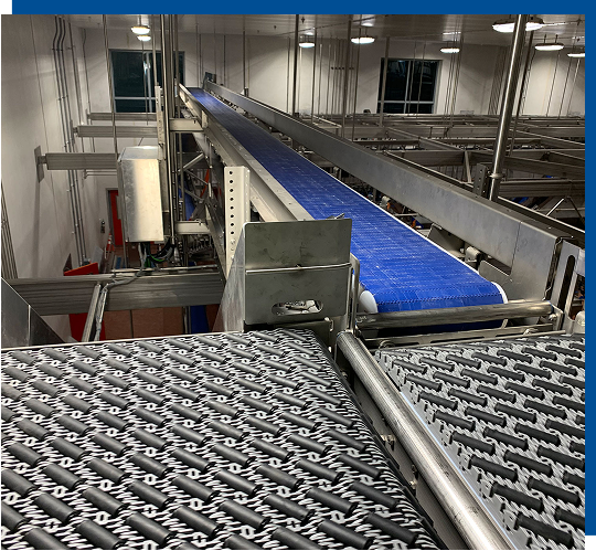 Conveyor system in a manufacturing facility featuring a blue conveyor belt and adjacent textured conveyor surface, illustrating CHL Systems' customized conveyance solutions for efficient material handling.