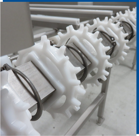 Industrial food processing machinery components, including white plastic gears and metal fittings, highlighting custom fabrication and parts sourcing by CHL Systems Inc.